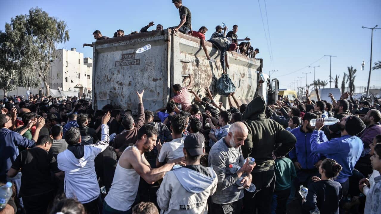 People surround a truck to try receive water bottles.