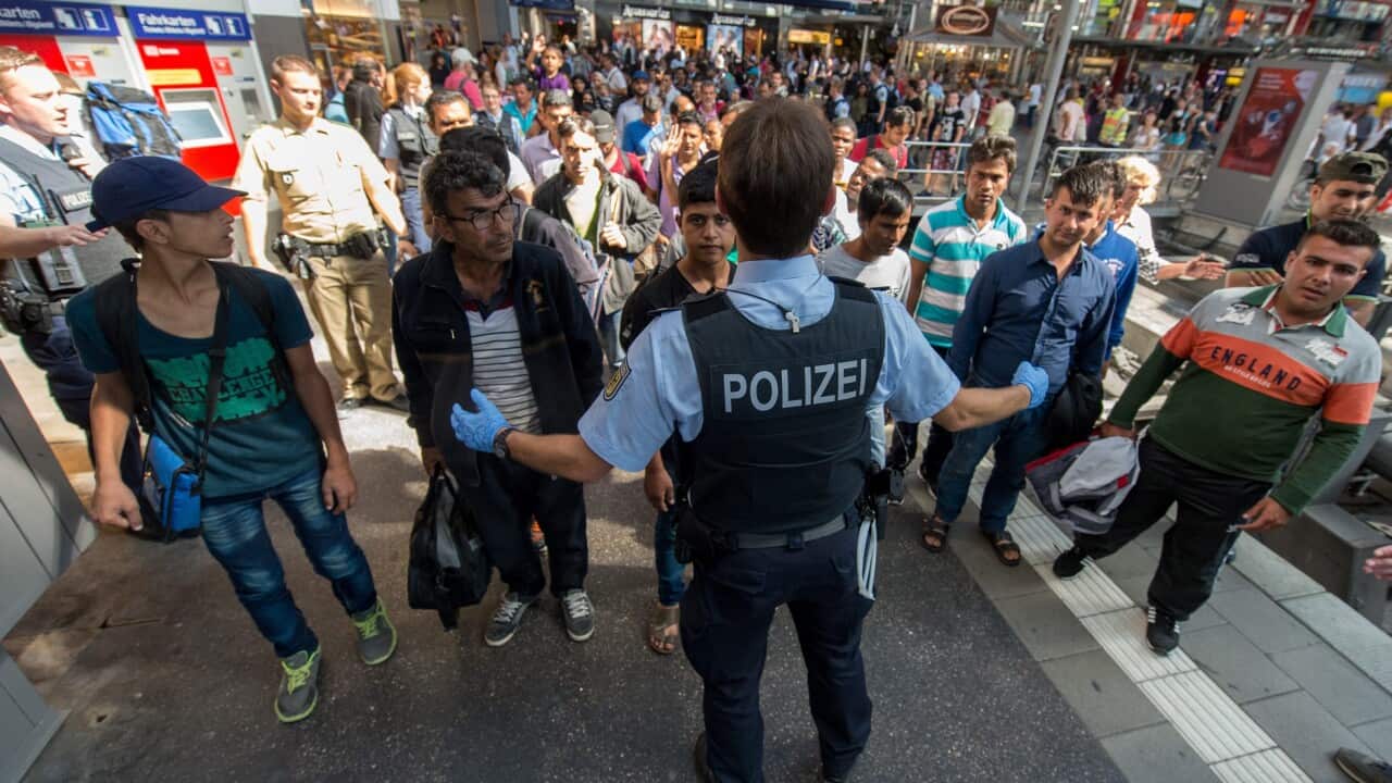 A policeman shows a refugee group the way to the registration office at the central train station in Munich, Germany, 31 August 2015. Between 50 and 60 refugees arrived on a train from Hungary via Austria.