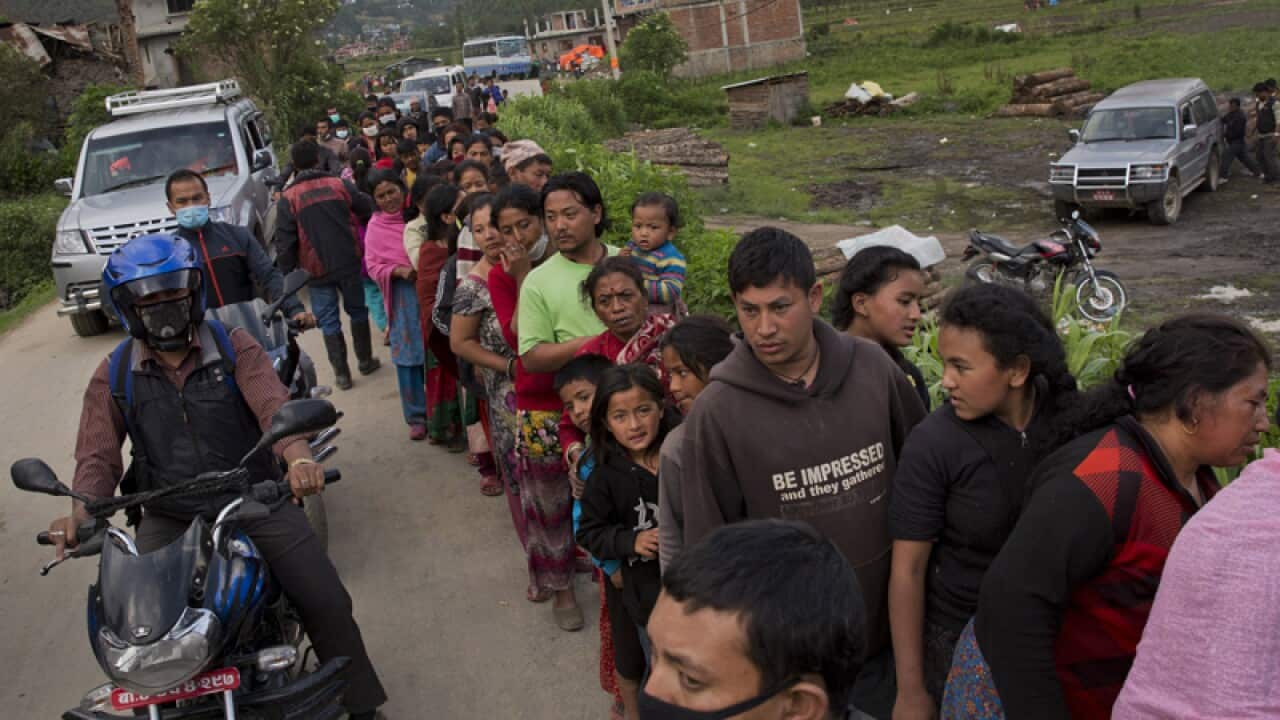 Nepalese villagers wait to receive food