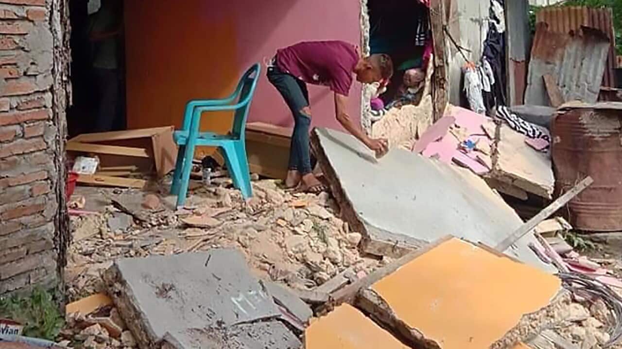 A resident inspects a collapsed wall of his house in Ambon.