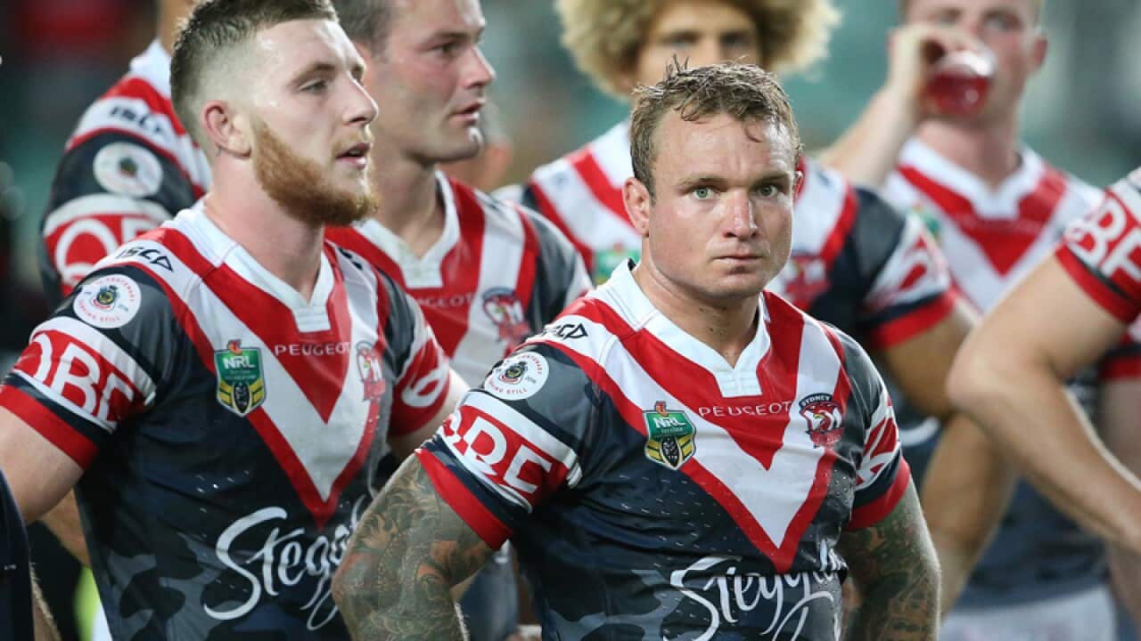Roosters players stand together after their defeat to the Dragons