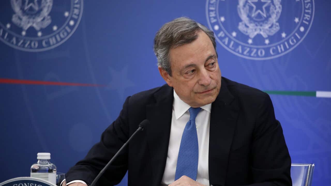 Prime Minister Mario Draghi sitting in front of a microphone
