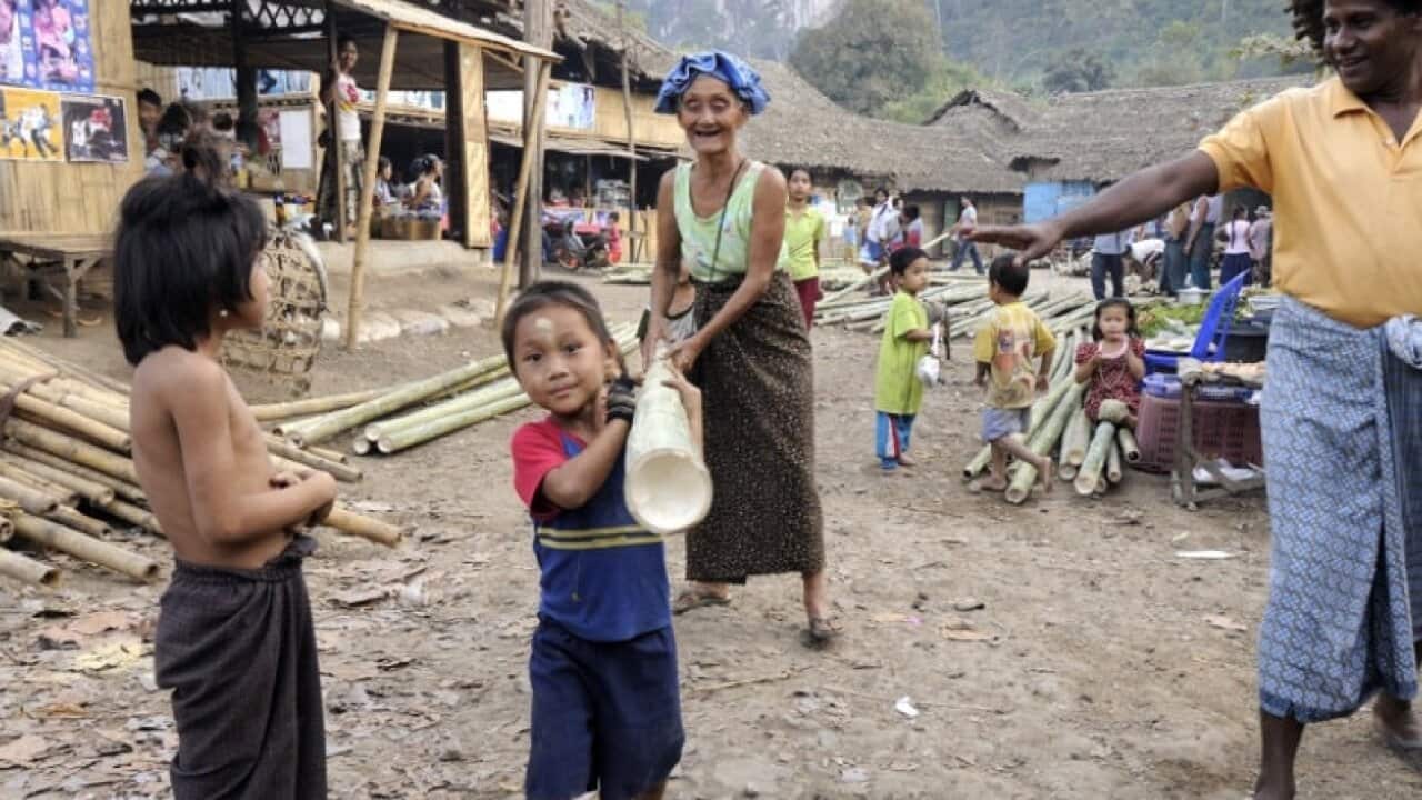 A boy wants to help his grandma caring the bamboo pole in Mae La camp.