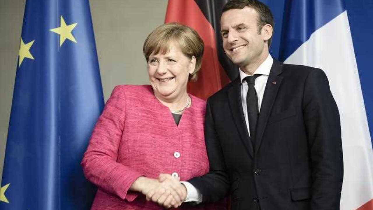 German Chancellor Angela Merkel (L) and newly elected French President Emmanuel Macron (R) pose for the photographers during a joint press conference