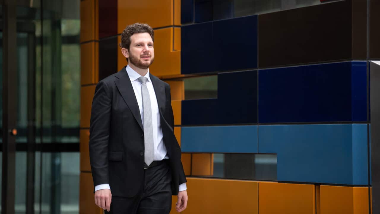 A Caucasian man in black suit walking out of court