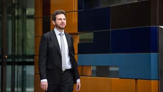 A Caucasian man in black suit walking out of court