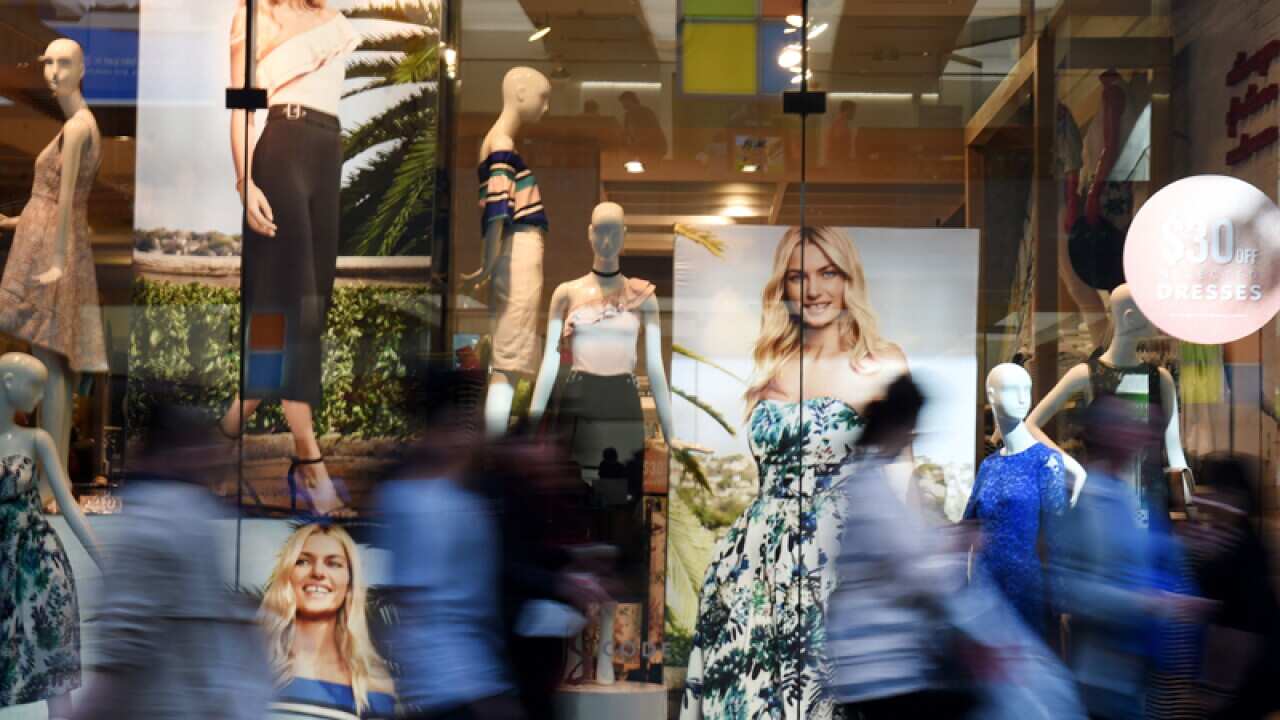 Pedestrians walk past a window display outside a store