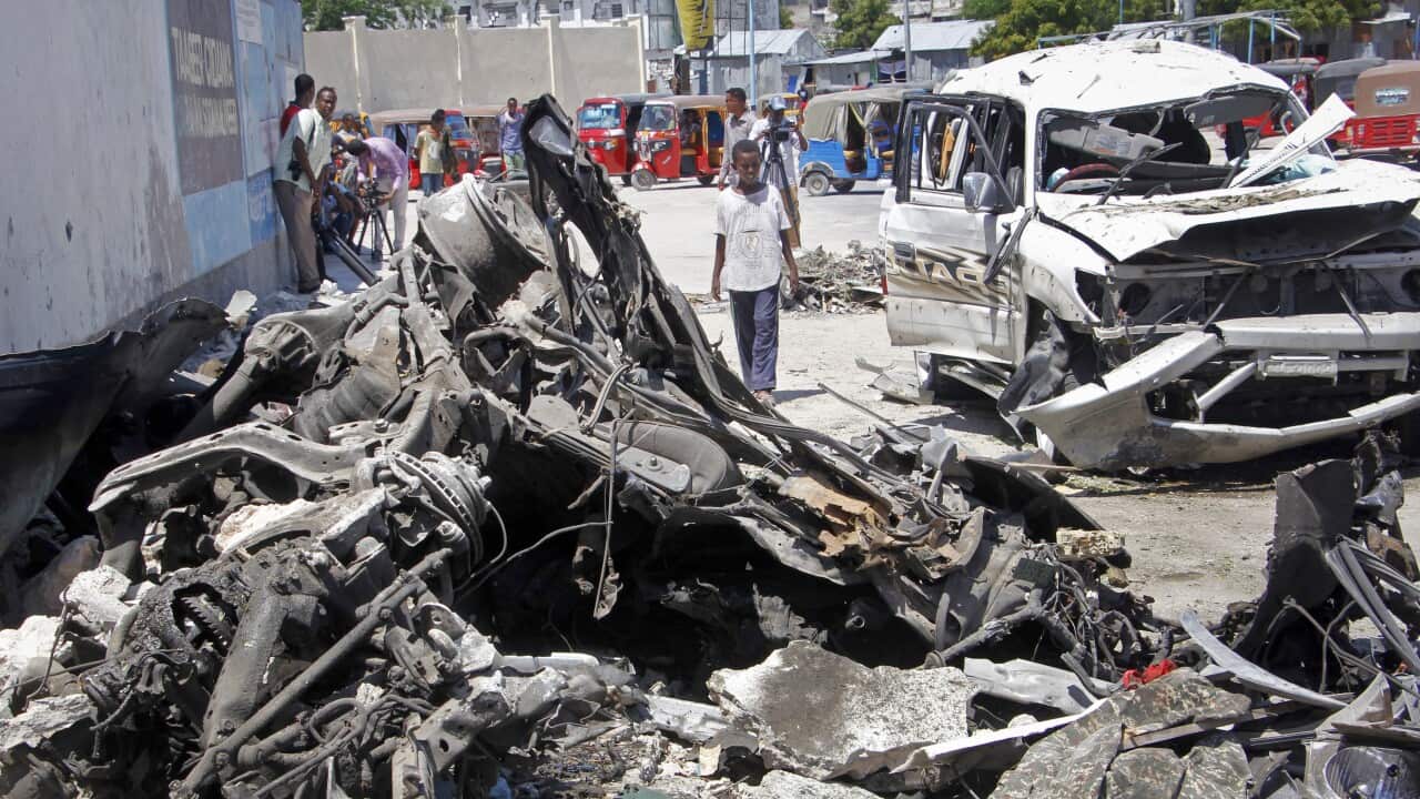 Somalis walk near the wreckage after a suicide car bomb attack in the capital Mogadishu.