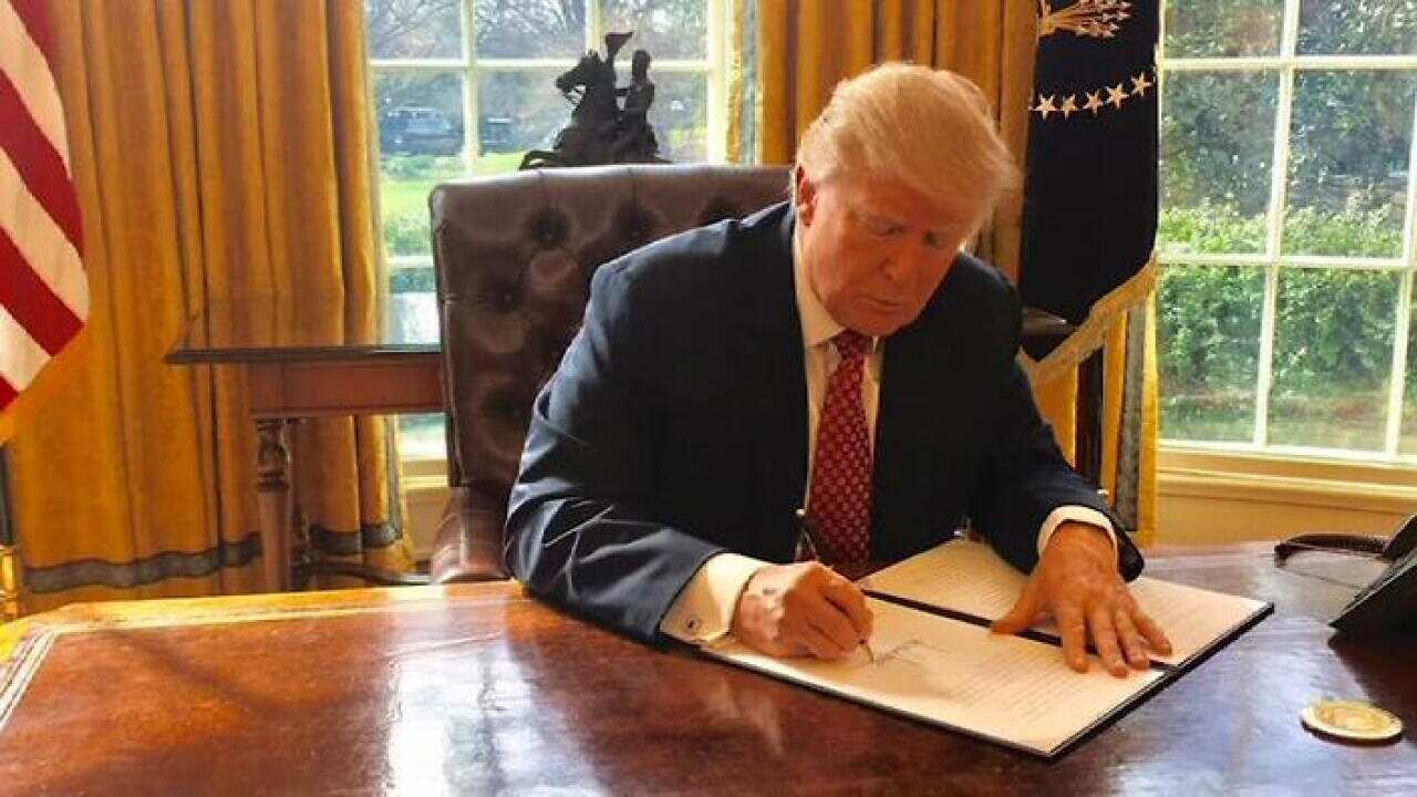 US President Donald Trump signs the revised immigration order. (CNN