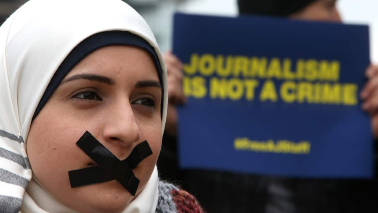 A journalist covers her mouth with tape during a sit in