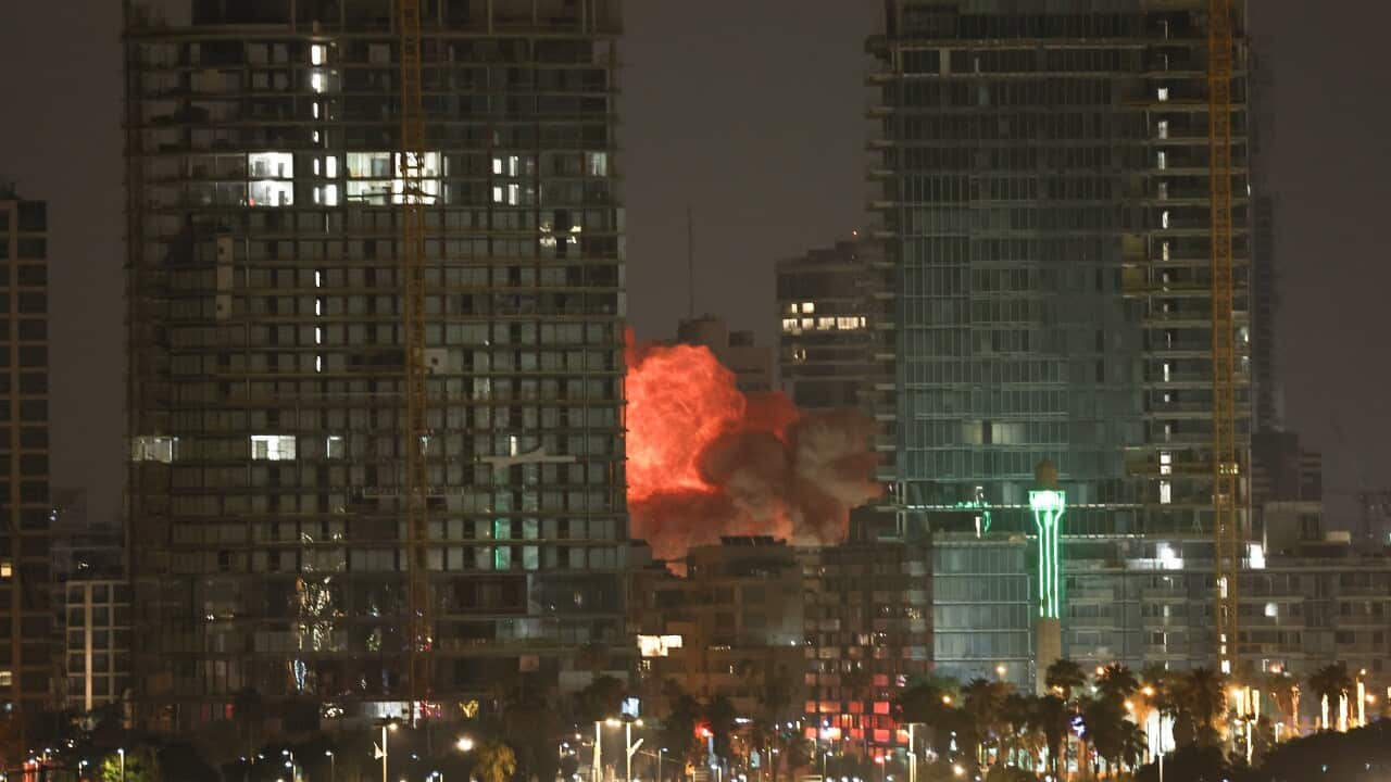 Thick plumes of smoke rise from a building flanked by high-rises.