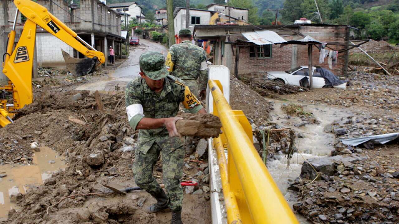 Mexican soldiers remove mud and debris off a bridge in Xaltepec