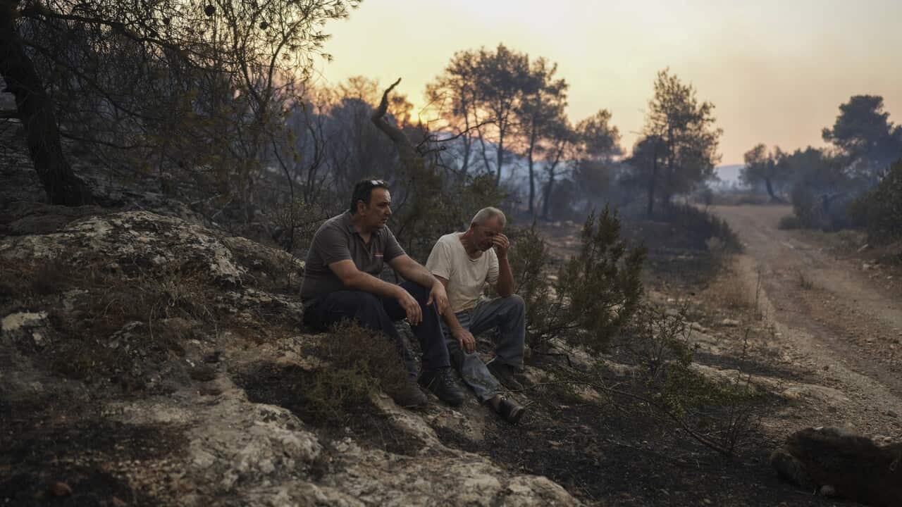 Two men sitting on burnt ground