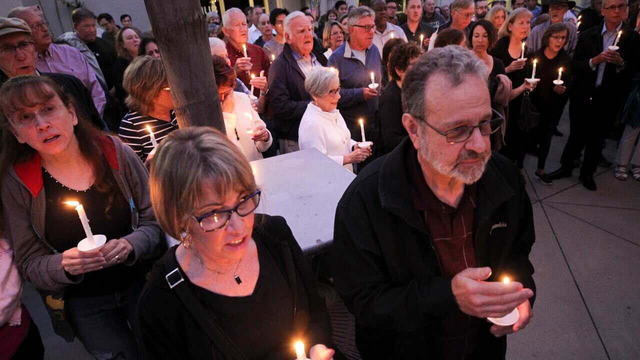 People from the community, many of them of various faiths, attend a candlelight vigil.
