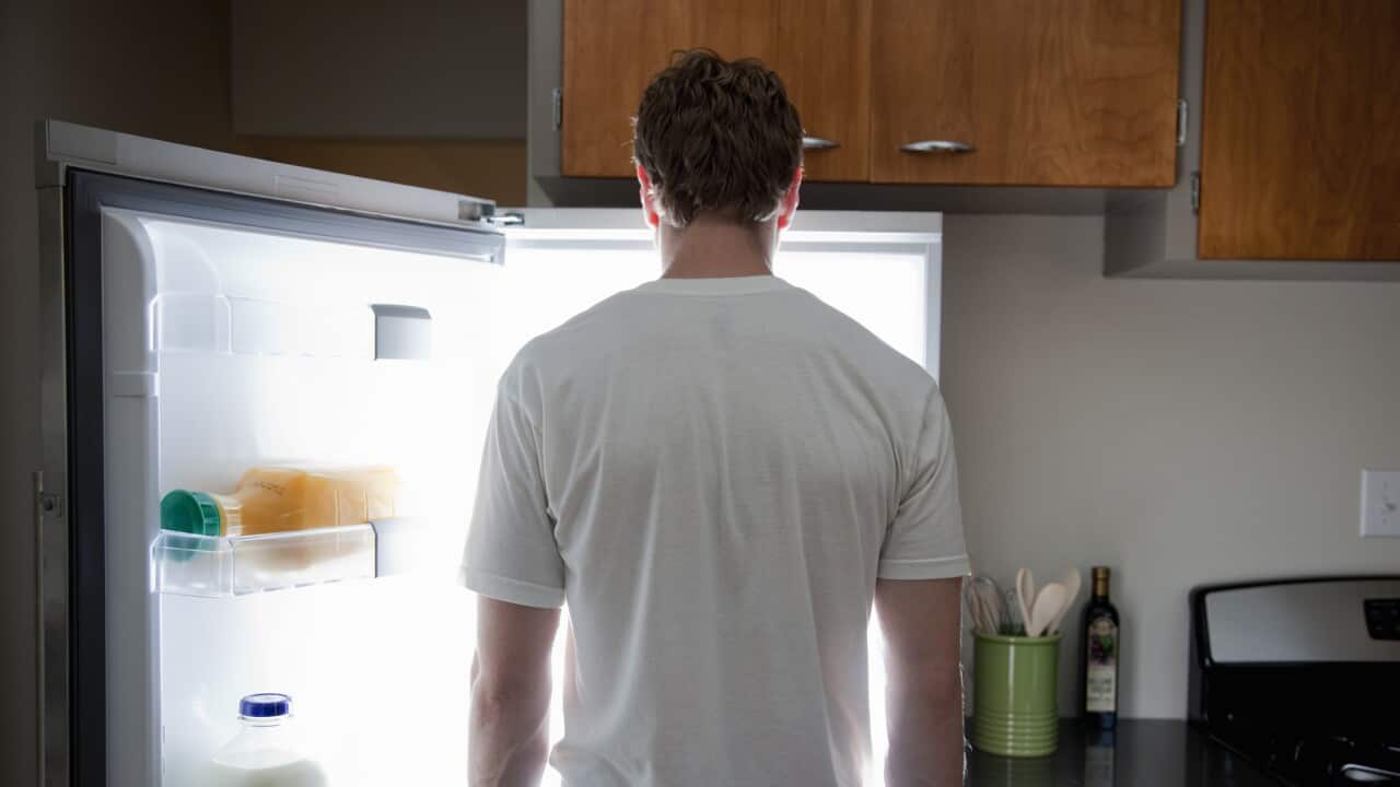 Man standing looking at contents of fridge