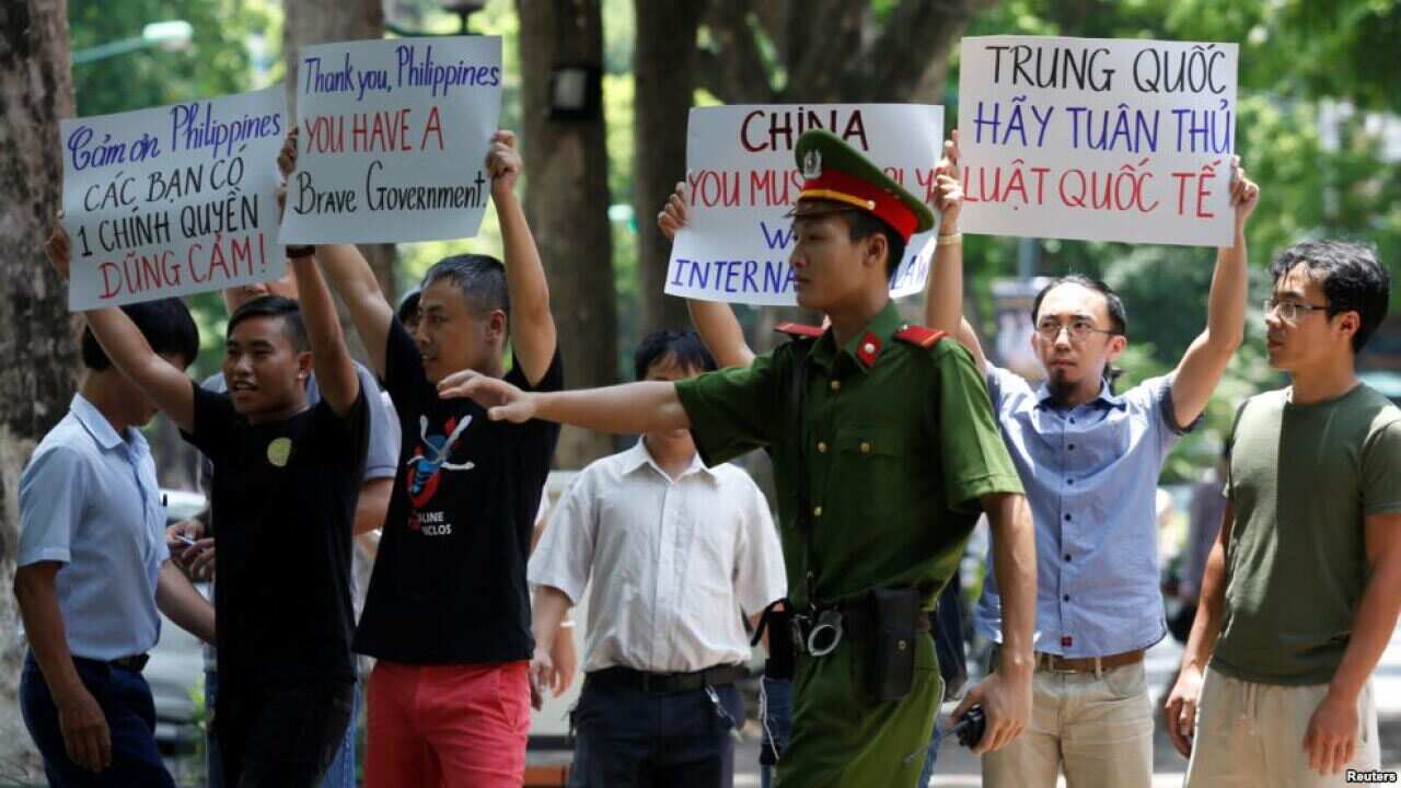 A policeman tries to stop anti-China protesters holding placards during a demonstration in Hanoi, Vietnam July 17, 2016.