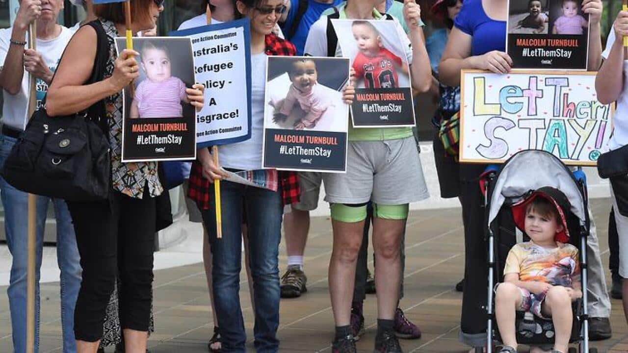 Asylum seeker advocates hold signs after the High Court of Australia ruling on refugees to Nauru in Canberra, Wednesday, Feb. 3, 2016. (AAP Image/Mick Tsikas) NO ARCHIVING