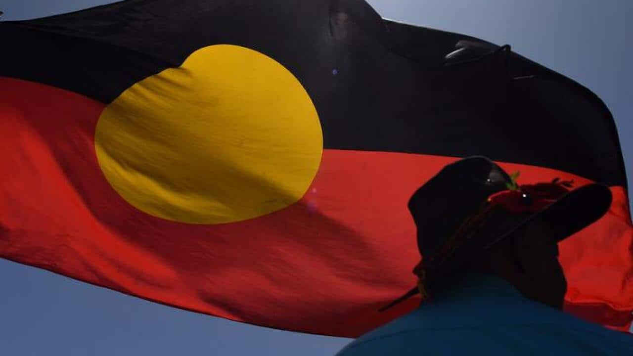 مردی در حال اهتزاز دادن پرچم ابورجینل در جلو پارلمان آسترالیا