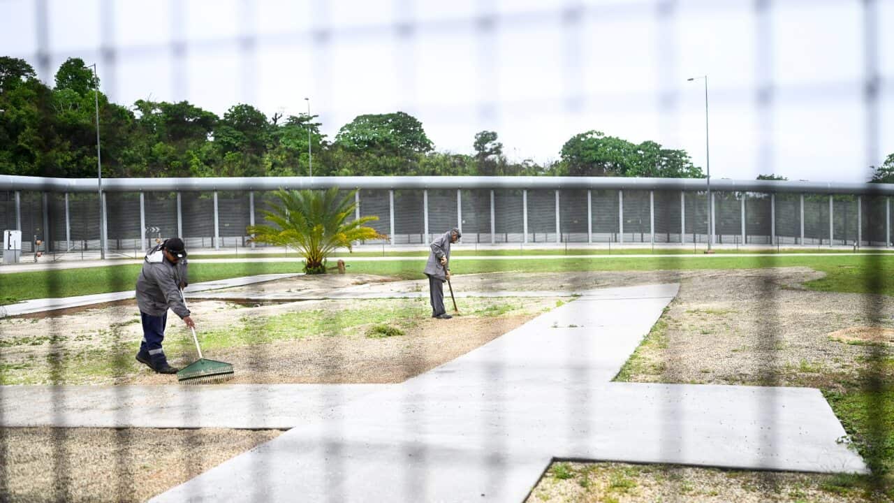 Staff work near the perimeter fence during a tour of the North West Point Detention Centre on Christmas Island