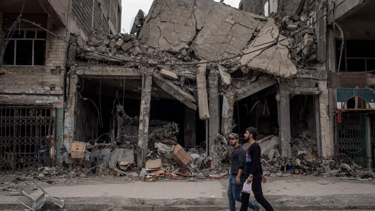 Men walk past destroyed buildings in Mosul.