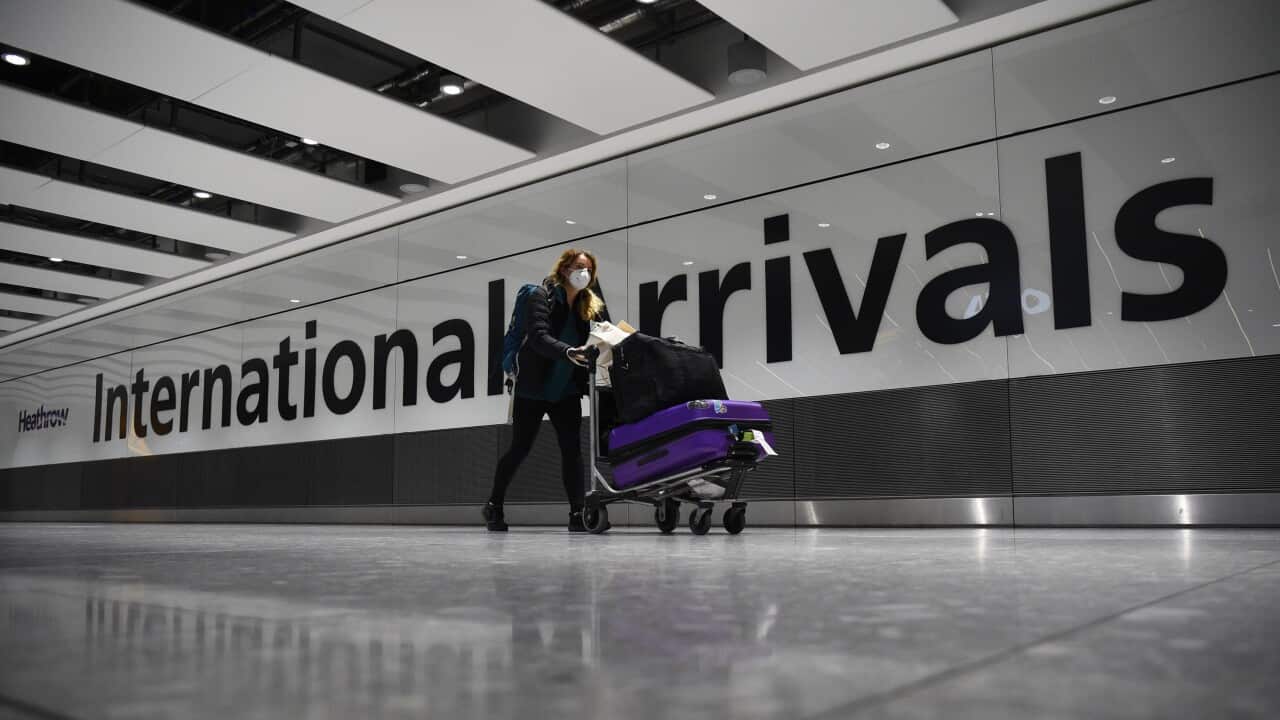 A passenger pushing luggage through the Arrival Hall of Terminal 5 at London's Heathrow Airport