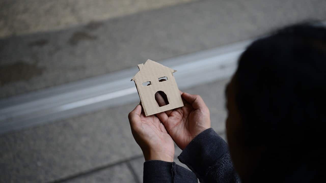 Hands of the man holding the paper house