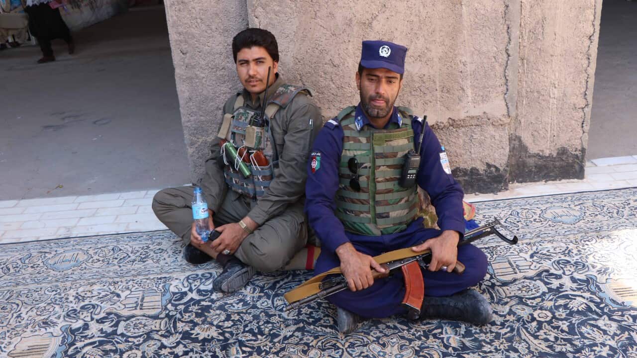 Afghan police officers sit as they guard a polling station during the Presidential elections in Herat, Afghanistan.
