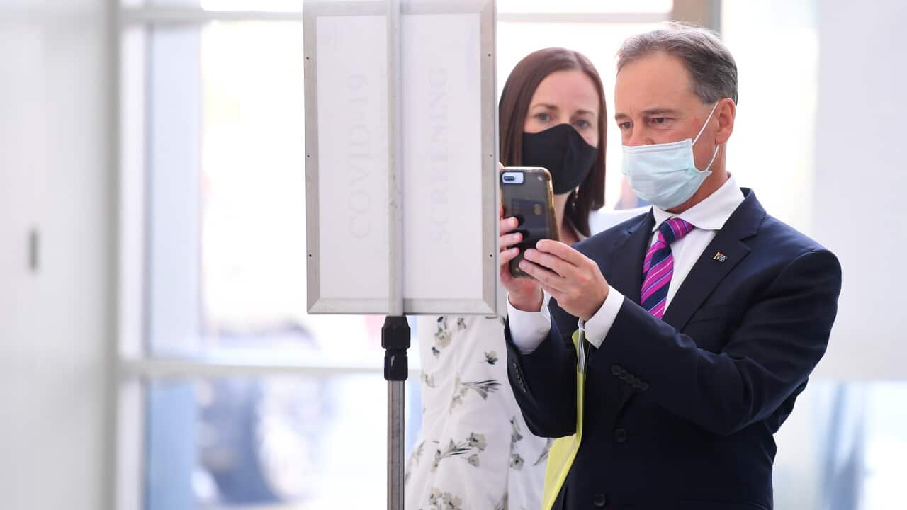 Minister for Health Greg Hunt (right) signs in using a QR code during a media tour