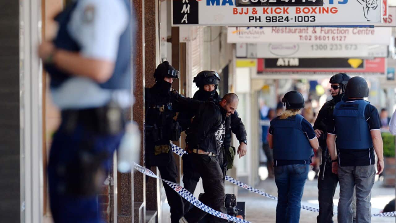 Police take a man into custody at the scene of a siege at a brothel