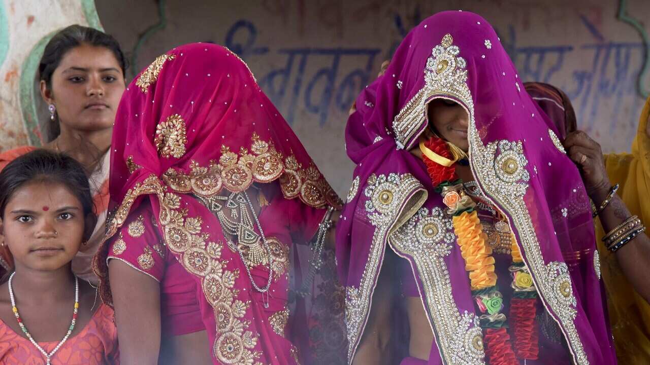 An underaged bride, right, stands with family members during her marriage at a Hindu temple near Rajgarh, Madhya Pradesh state, India.