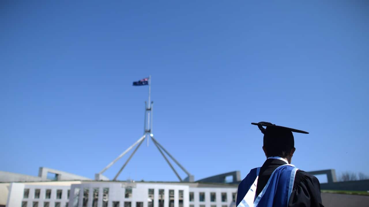 A man wearing a graduate suit outside federal parliament