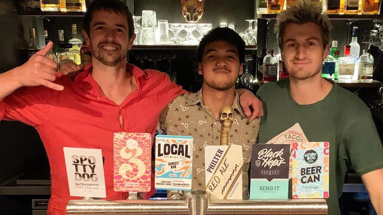 Rezon Juliodionko (C) with the owners of Grinners Dive Bar in Hobart.