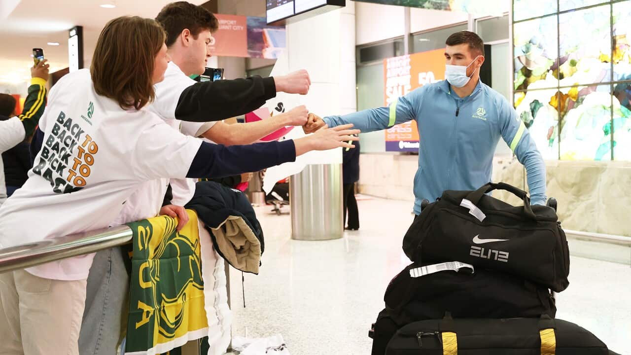 A man fist-bumping a person as he walks through an airport terminal.