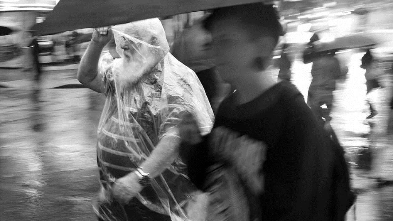 Pedestrians walk through rainy weather in Brisbane