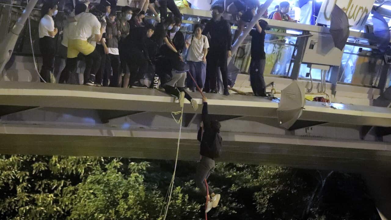 Protestors use a rope to lower themselves from a pedestrian bridge to waiting motorbikes in order to escape from Hong Kong Polytechnic University.