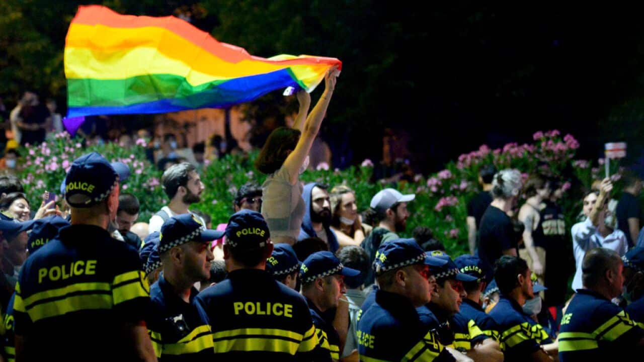 A participant holds a rainbow flag next to police during a rally in support of those who were injured during the 5 July protests in Tbilisi.