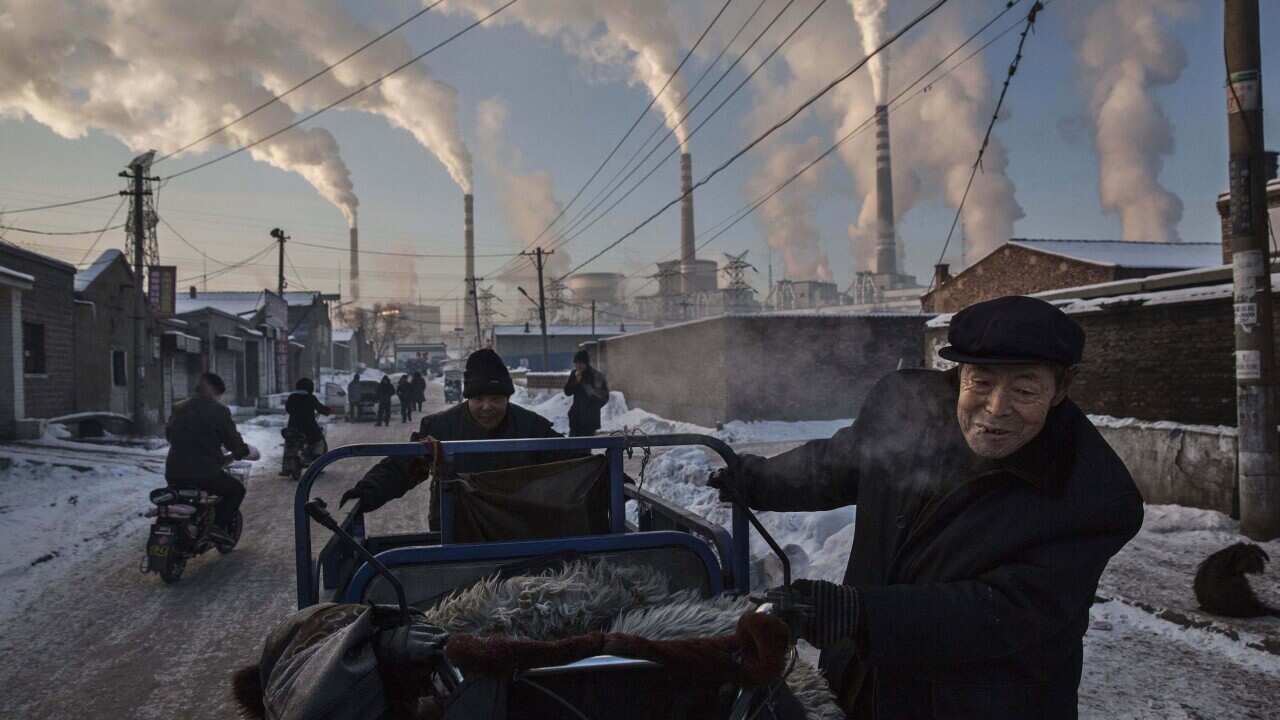 Chinese men pulling a tricycle in a neighborhood next to a coal-fired power plant in Shanxi, China, on Nov. 26, 2015.