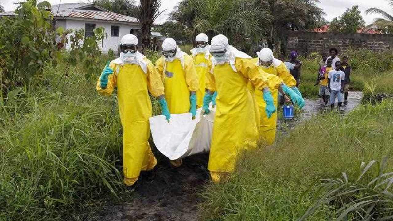 Liberian nurses carry a dead body suspected of dying from the Ebola virus at the Roberts field highway on the outskirts of Monrovia, Liberia, 25 September 2014.