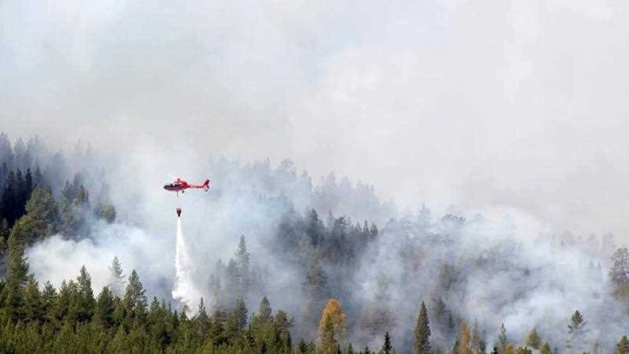 A picture made available on 17 July 2018 shows a helicopter water-bombing a forest fire raging in Hammarstrand, Sweden, 16 July 2018.