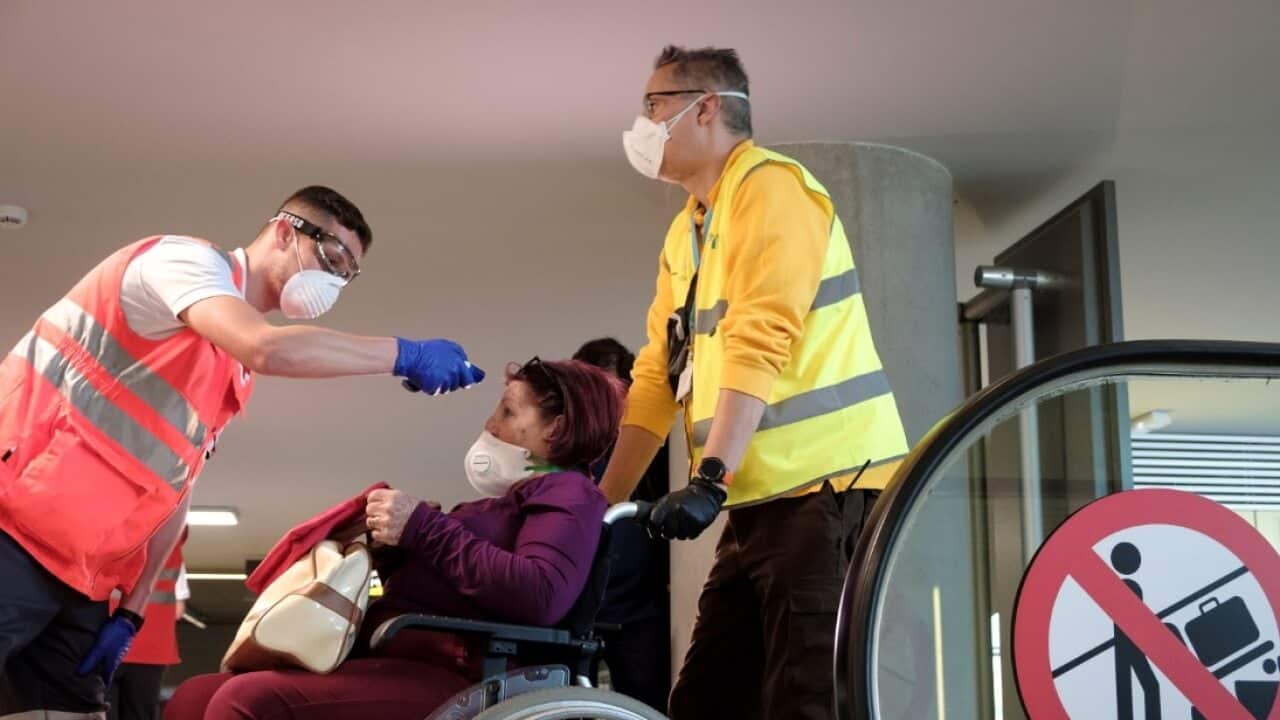 Red Cross members check the body temperature of the passengers of a flight from Madrid upon arrival at Gran Canaria's airport, in Canary Islands