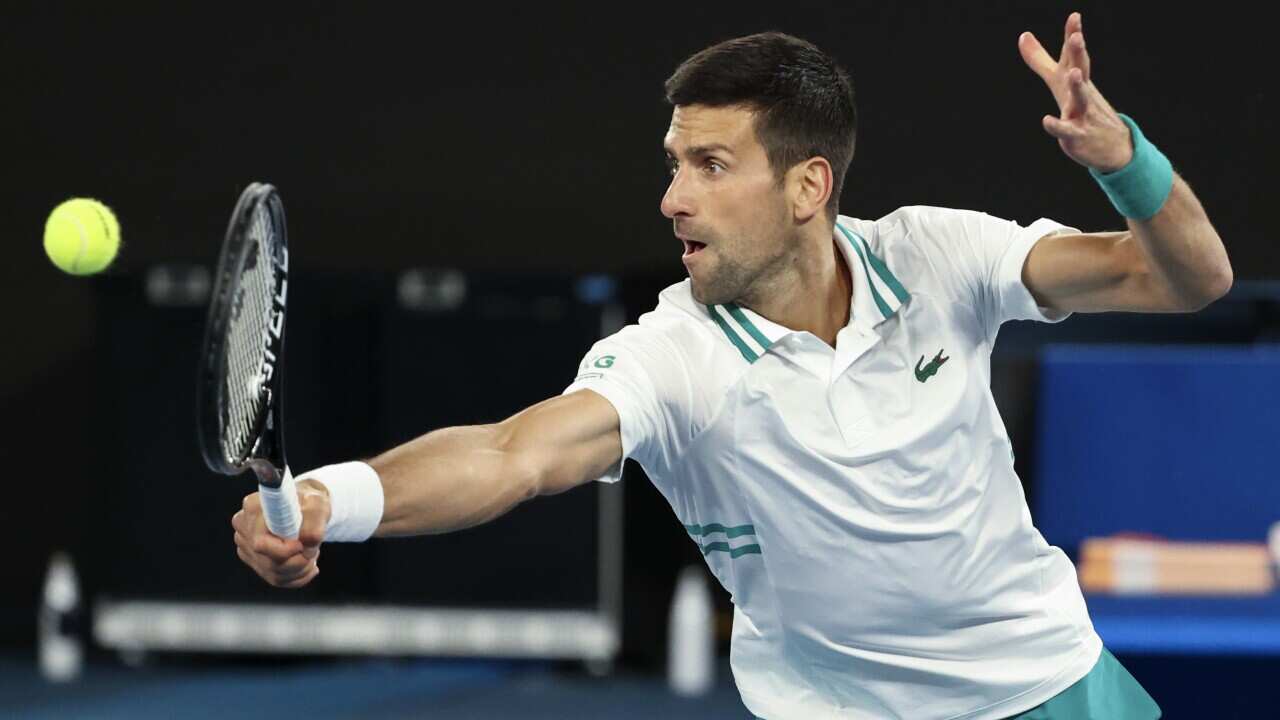 Serbia's Novak Djokovic hits a backhand return to Canada's Milos Raonic during their fourth round match at the Australian Open tennis championship in Melbourne, Australia, Sunday, Feb. 14, 2021.(AP Photo/Hamish Blair)