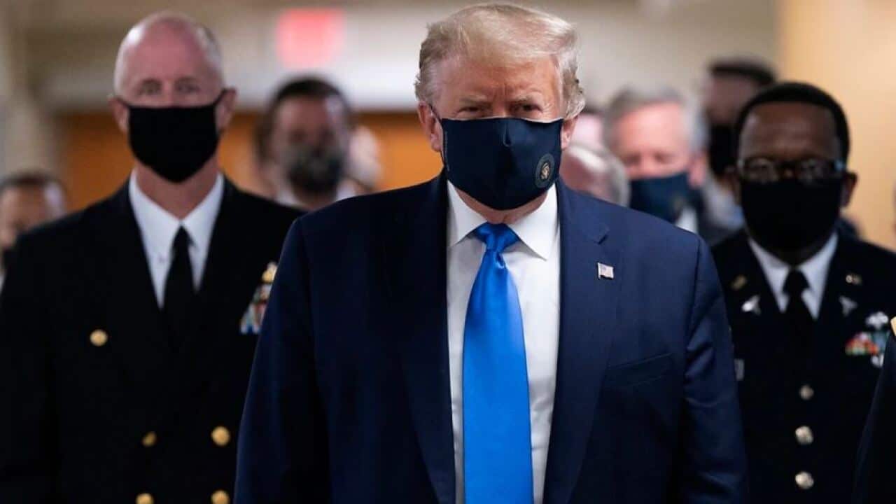 US President Donald J. Trump wears a face mask as he arrives to visit with wounded military members and staff at Walter Reed National Military Medical Center.