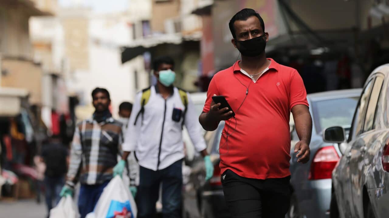 People wearing protective face masks walk in a street of Manama, Bahrain.