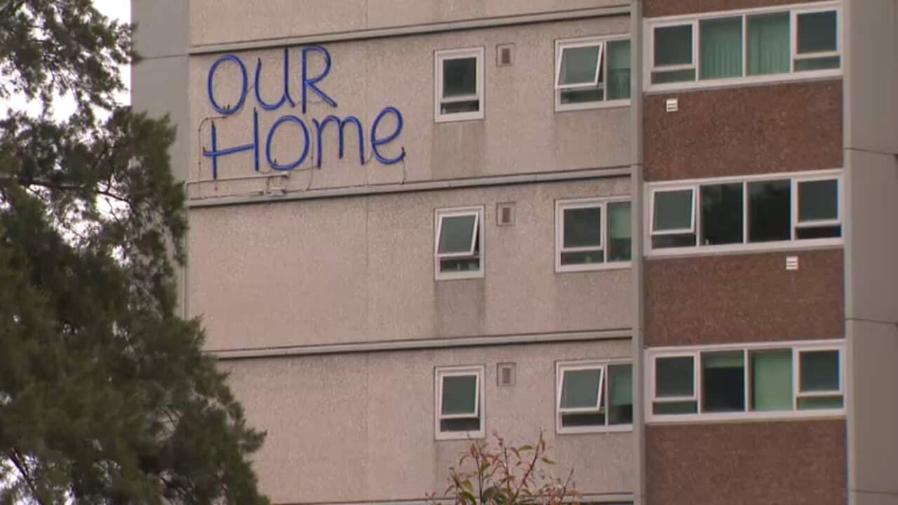 Exterior of one of the housing commission towers in North Melbourne, sign reads OUR HOME.