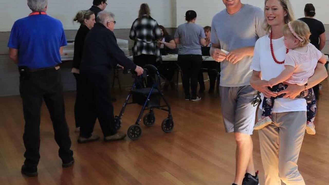 Rebecca White walks to the ballot box with her husband and daughter.