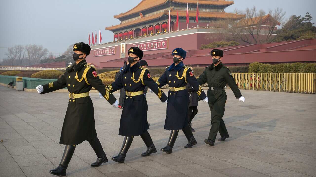 Security officials wear face masks as they march in formation near Tiananmen Gate adjacent to Tiananmen Square in Beijing, Monday, Jan. 27, 2020. China on Monday expanded sweeping efforts to contain a viral disease by postponing the end of this week's Lun