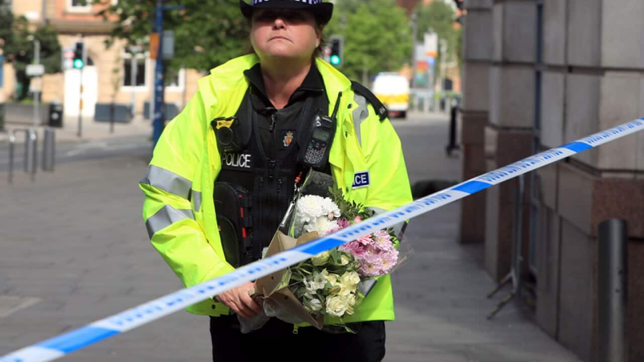 A police officer moves a floral tribute close to the Manchester Arena