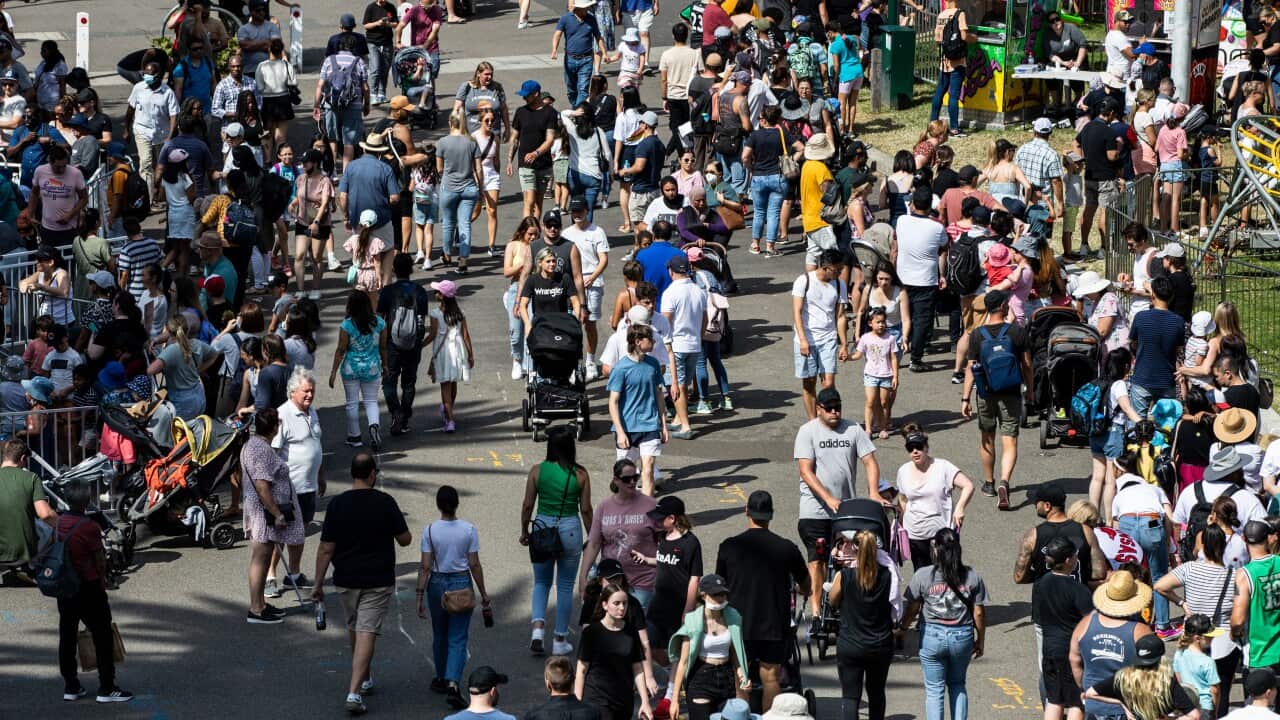 People are seen walking along a riverbank during a festival.