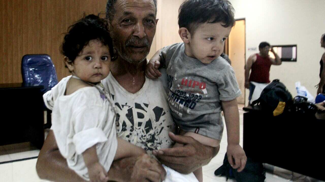 Asylum seeker Abdel Emir carries his children