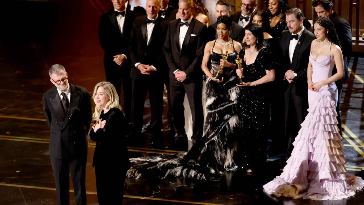 A group of people in formal wear standing together on a stage.
